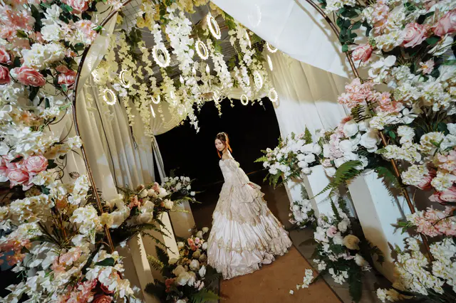 Debutante in a blue gown in the garden at night, under strings of festoon lights